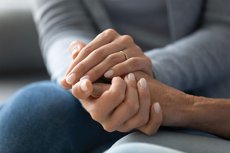 daughter holding elderly mothers hand