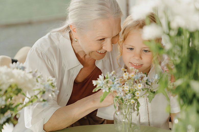 grandmother arranging flowers with granddaughter