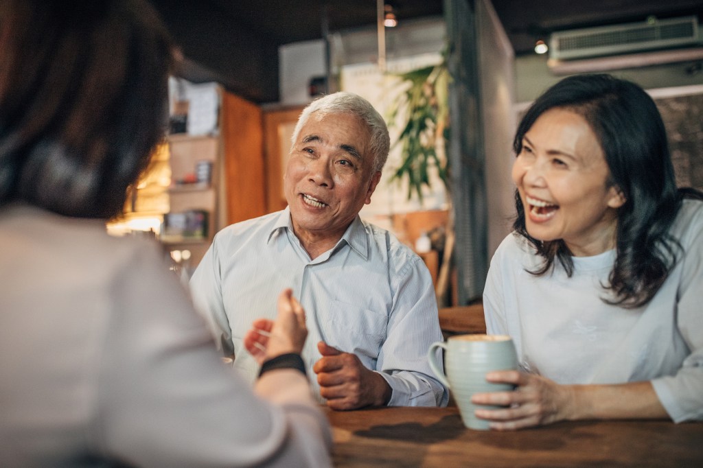 Three senior friends are sitting in a cafe, drinking coffee. 