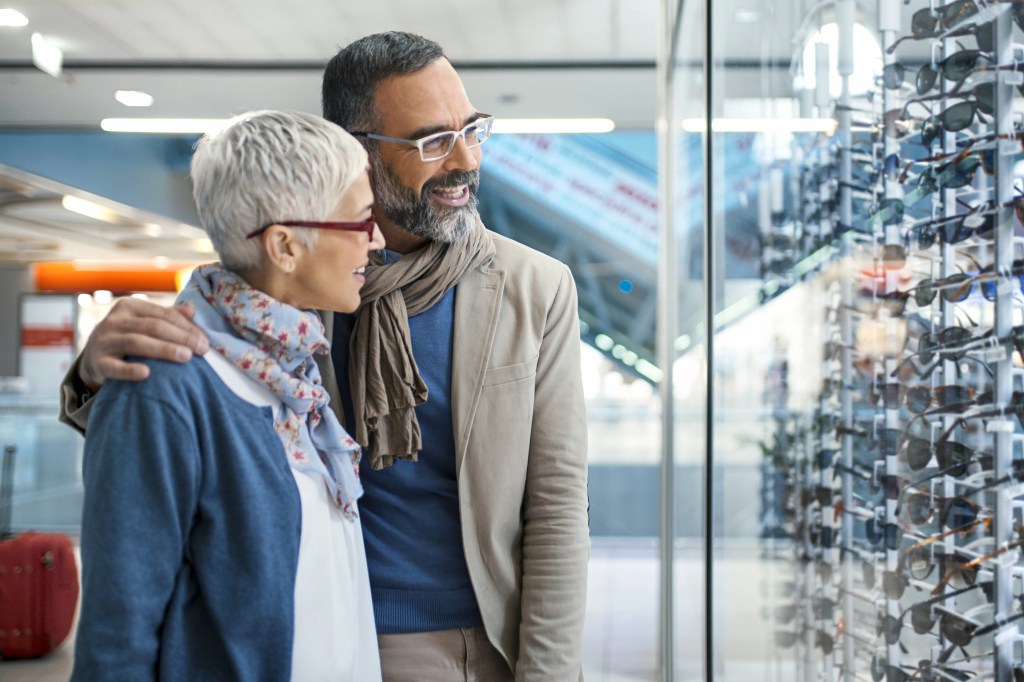 A middle-aged man and woman are shopping for sunglasses.