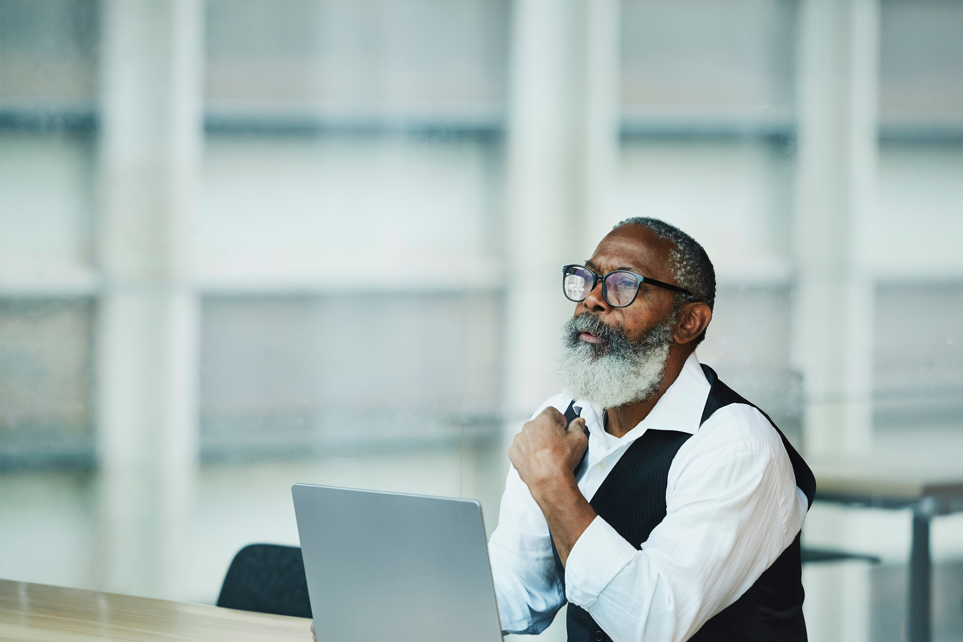 a professional business man with thick black framed glasses working at a laptop