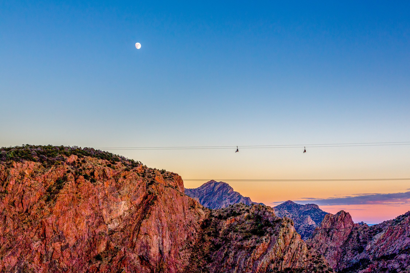 people ziplining at sunset