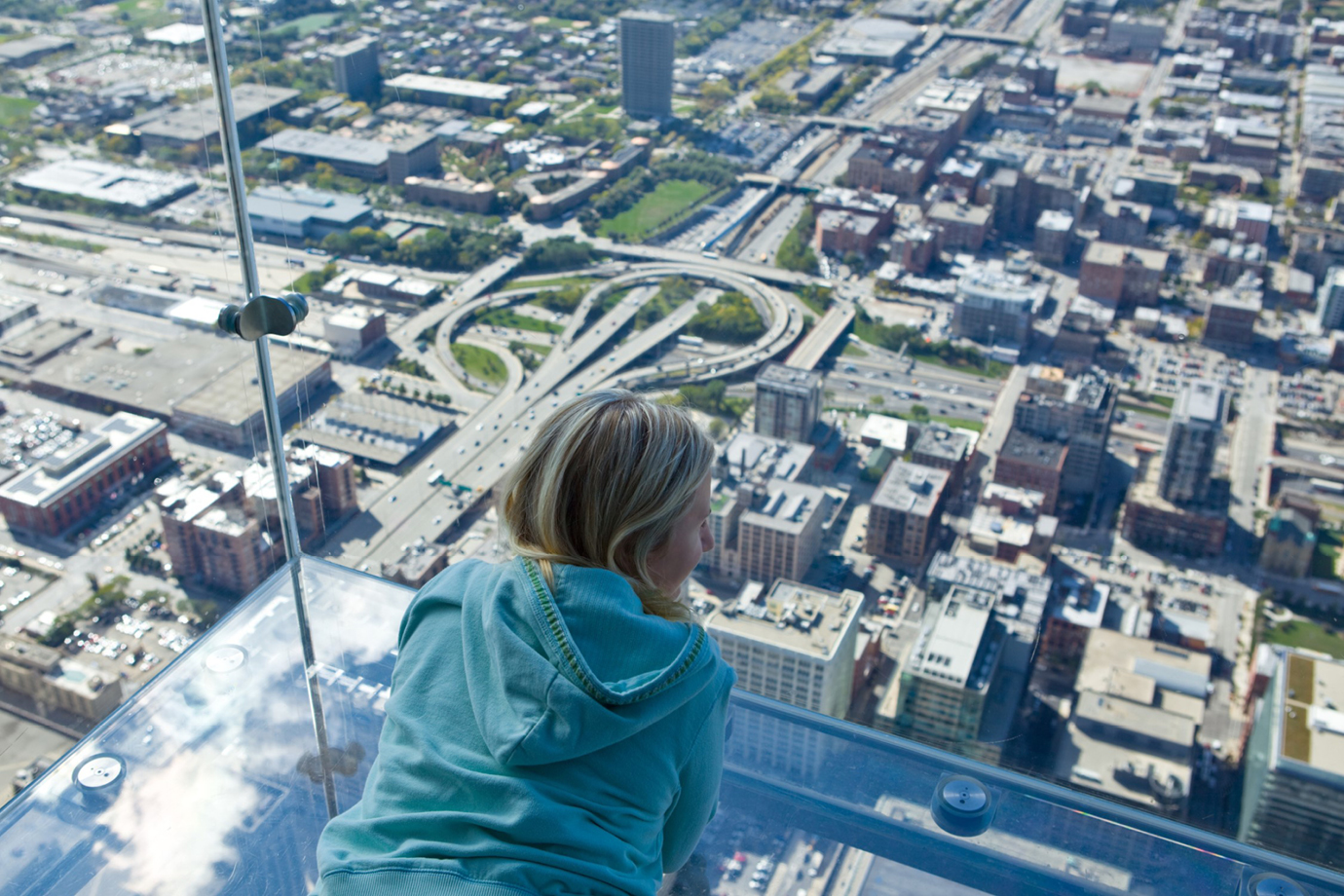 young woman looking out through glass skydeck