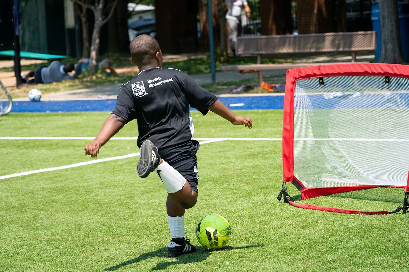 Photo of young soccer player kicking a ball in net.