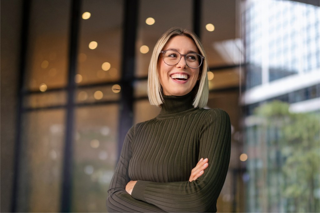 smiling young millennial woman with arms folded