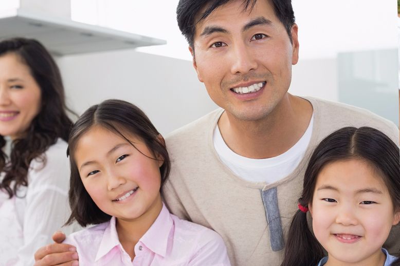 father smiling with two daughters