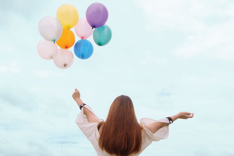 woman holding multicoloured balloons