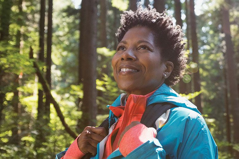 woman hiker in the woods holding backpack straps