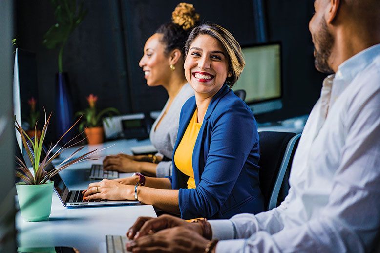 three smiling coworkers on computers