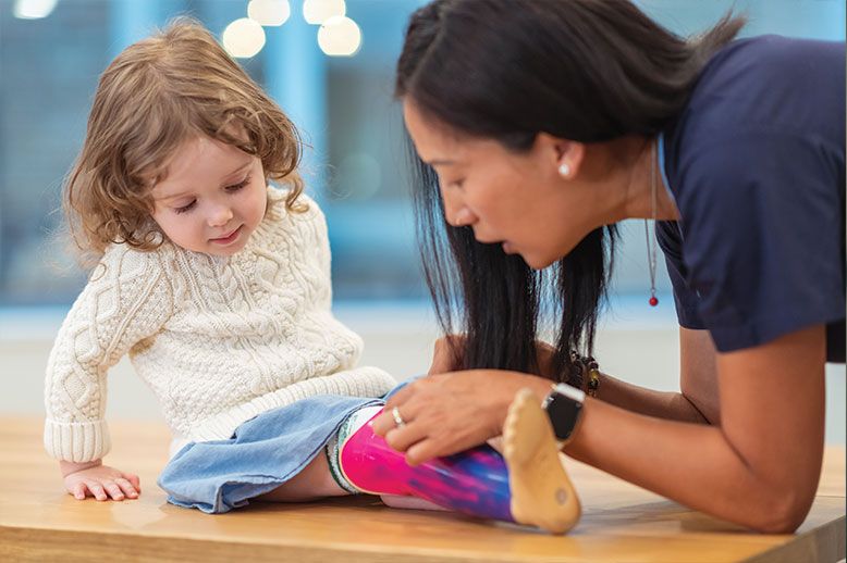 woman tending to child with prosthetic leg